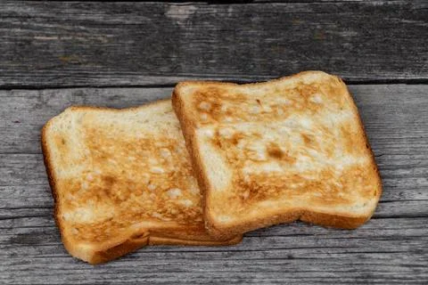 Two square ruddy pieces of bread for toasts on the old gray wooden background Stock Photos