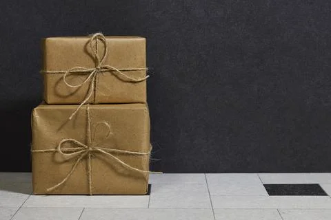 Two Stacked Brown Gift Boxes Wrapped in Twine Against a Dark Minimal Background Stock Photos