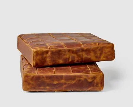 Two stacked functional brown leather square seat cushions on white Stock Photos