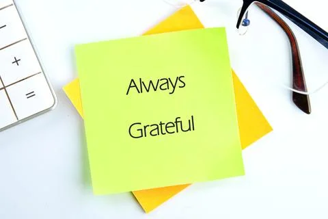 Two stacked sticky notes sit on a white desk. A light green note on top reads Stock Photos