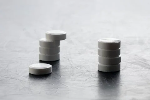 Two stacks of pills next to each other on gray table. medical drug concept Stock Photos