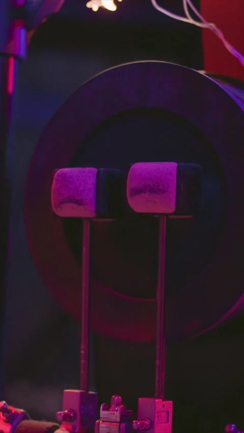 Two stationary drum pedals with felt covers under moody purple and pink ambient Stock Footage 346795232