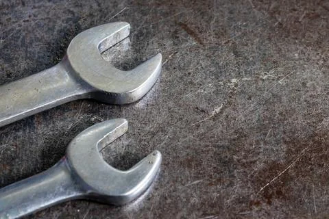Two steel open end wrenches lie on scratched metal workbench in industrial .. Stock Photos