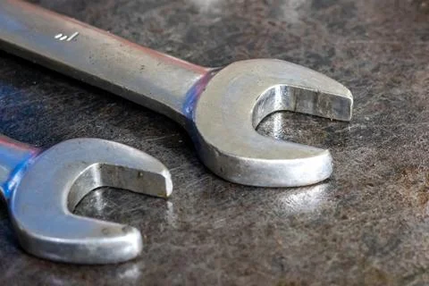 Two steel open end wrenches lie on scratched metal workbench in industrial .. Stock Photos