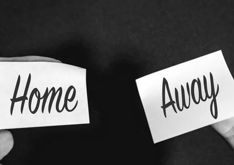 Two sticky notes on a black background, with Home and Away on it Stock Photos