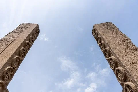 Two stone pillars with faces carved into them stand in front of a blue sky Fotos Stock