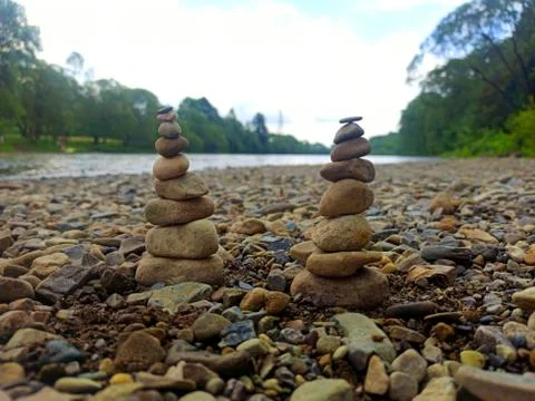 Two stone pyramids on a background of blue sky and river. The concept of bala Stock Photos