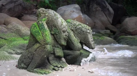 Two Stone Statues in the Moss on the Beach, Lapped by the Waves. Slow Motion Stock Footage 66307063