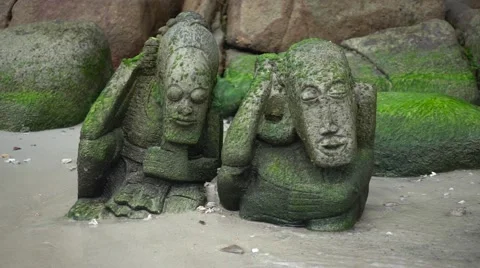 Two Stone Statues in the Moss on the Beach, Lapped by the Waves. Slow Motion Stock Footage 66309715