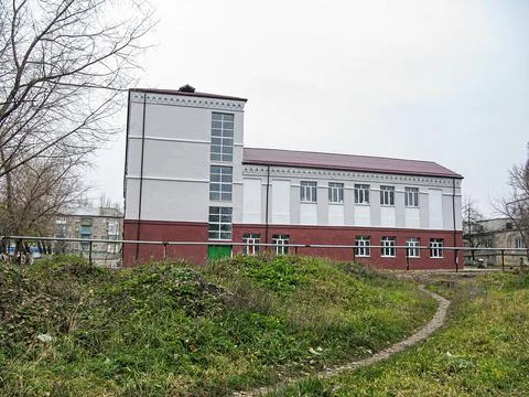 A two-story building with gray upper and red brick lower parts, multiple wind Stock Photos