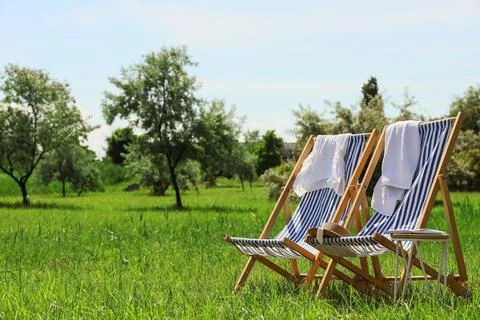 Two striped deck chairs with towels in green meadow Stock Photos