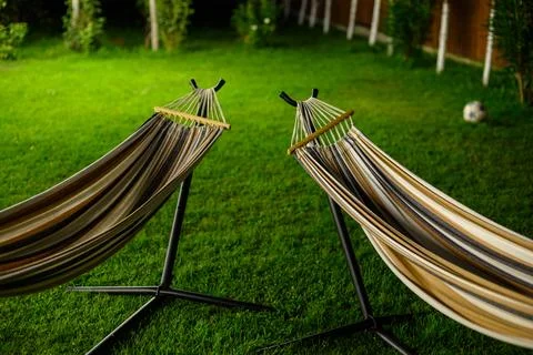 Two striped hammocks set up on a lush, vibrant green lawn, facing each othe.. Stock Photos