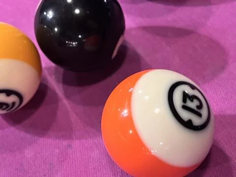 Two stripes pool balls and the black on a pink pool table Stock Photos