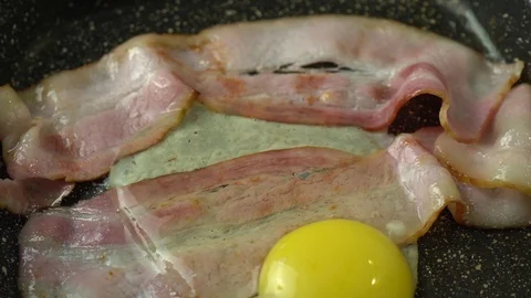Two strips of bacon frying in a pan with an egg Stock Footage 125930892