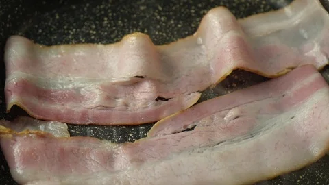 Two strips of bacon frying in a pan Stock Footage 125931920