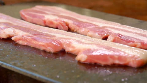 Two strips of raw bacon are roasted of the grill Stock Footage 104508679
