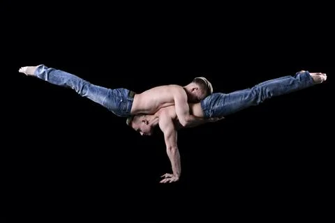 Two strong acrobats perform the element of scales, handsome young guys. jean Stock Photos