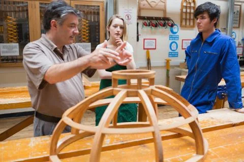 Two students and an explaining teacher in a woodwork class Stock Photos