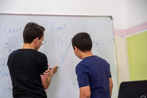 Two students are studying together using the whiteboard in school Stock Photos