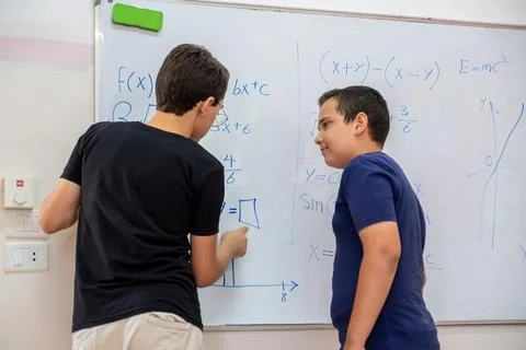 Two students are studying together using the whiteboard in school Stock Photos