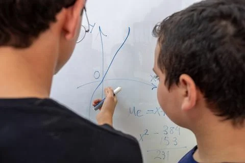 Two students are studying together using the whiteboard in school Stock Photos