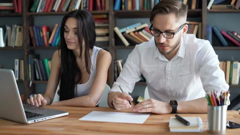 Two students brainstorming work by discuss with desktop in hipster loft closeup Video stock 199491634