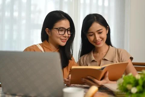 Two students doing homework together and using laptop for searching online Stock Photos
