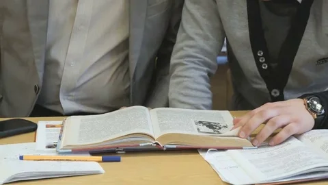 Two students flip pages of textbook at lesson Stock Footage 69232975