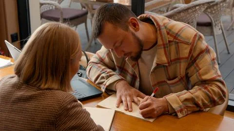 Two students focused on documents and making notes together in a cafe Foto stock