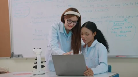 Two students in lab coats collaborate with a laptop Stock Footage 339406485