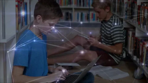 Two students in library typing on laptop, tapping tablet, causing drifting node Stock Footage 331214063