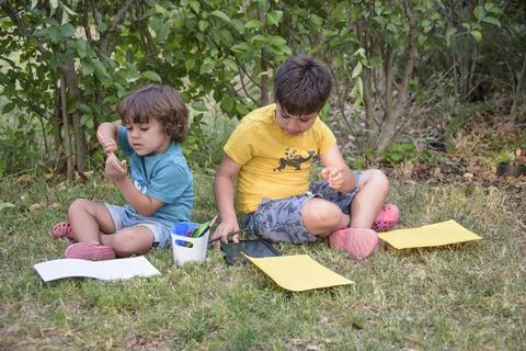 Two students lying in a park with their backpacks, one of them writing in a Stock Photos