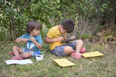 Two students lying in a park with their backpacks, one of them writing in a Stock Photos