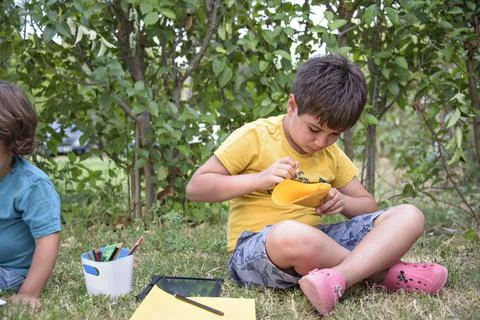 Two students lying in a park with their backpacks, one of them writing in a Stock Photos