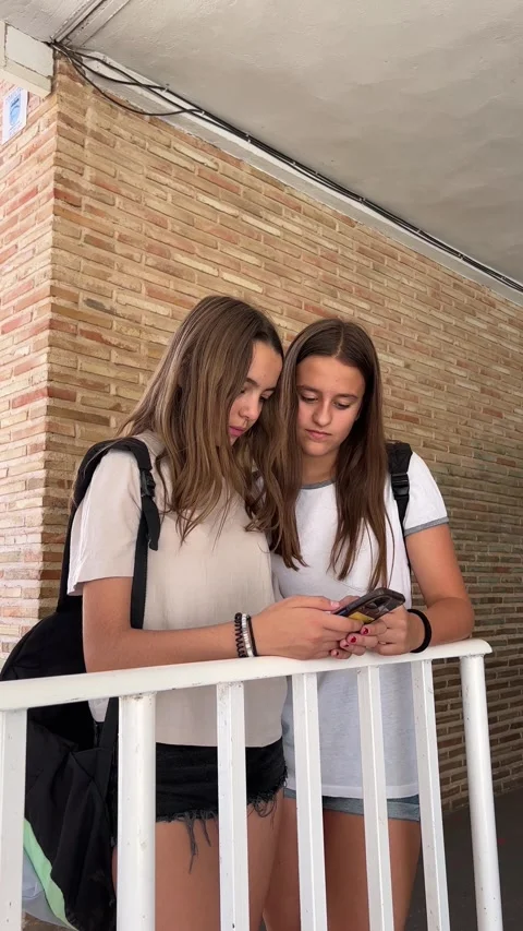 Two students at the school gate using mobile phones Stock Footage 248956798