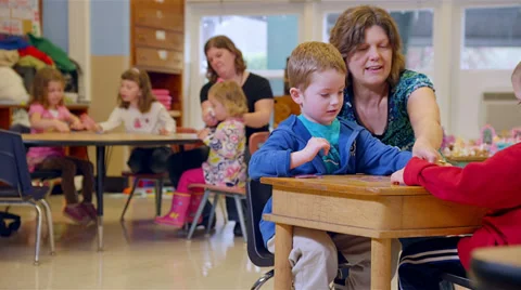 Two students sit with their teacher at a desk and play the game memory together Stock Footage 34004541