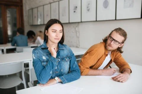 Two students sitting at the desk in classroom and writing test. Young man in Stock Photos