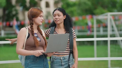 Two students stand outdoors, one holding a laptop Stock Footage 340448754