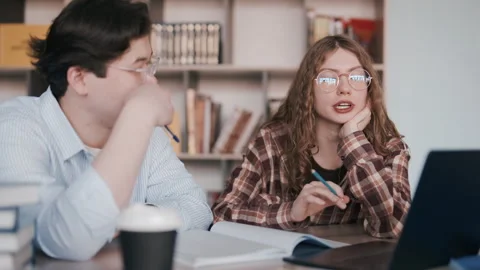 Two students study together at a desk with laptop and notebook in a classroom Stock Footage 341337610