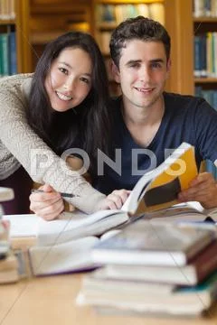 Two students studying at a desk in a library Stock Photos