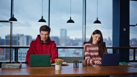 Two students studying laptops sitting table open space. Young man asking woman Stock Footage 340072220