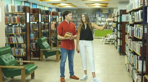 Two students walk through the library and choose books Stock Footage 68575407