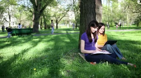 Two students working together with book and tablet outside, tracking shot HD Stock Footage 11056320