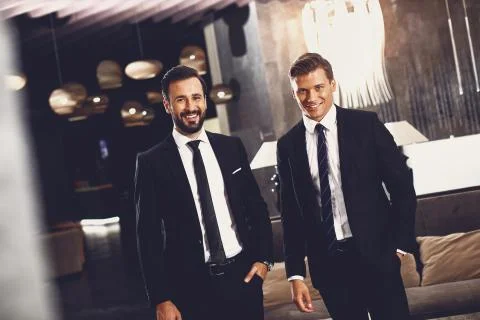 Two stylish men smiling while standing in the hall together Stock Photos