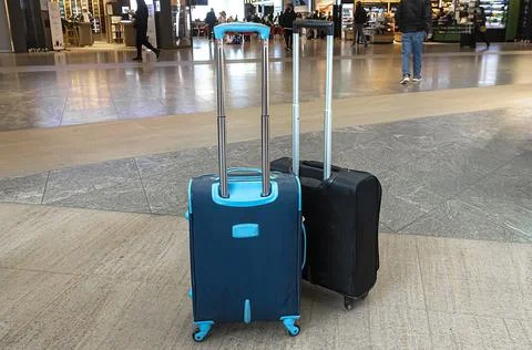 Two stylish suitcases stand in an empty airport hall, unrecognizable traveler Stock Photos