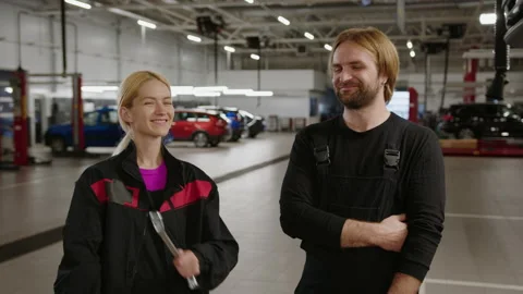 Two successful auto mechanics in uniform look at the camera and smile Stock Footage 240074352