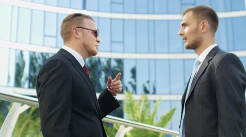 Two successful businessman talking while standing near office building Stock Footage 52820841