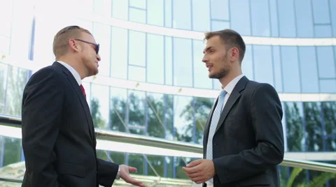 Two successful businessman talking while standing near office building Stock Footage 52820969