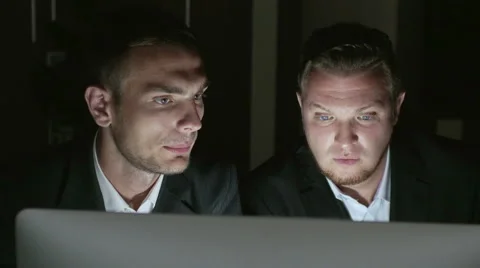 Two successful businessmen sitting at the computer at night Stock Footage 54935886
