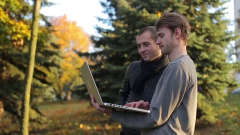 Two successful male programmers discussing using laptop during lunch break in Stock Footage 73904936